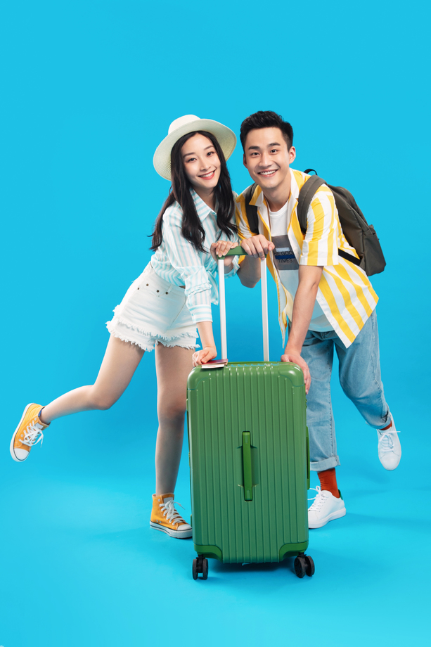 快乐的青年情侣一起推着行李箱去旅游