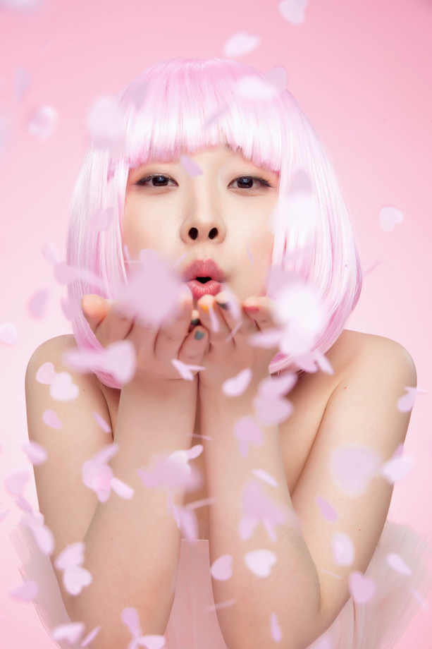 年轻女孩吹撒手中的心形纸片图片