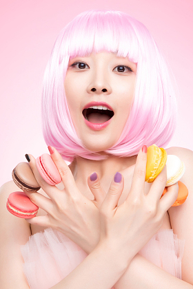 手指夹着马卡龙的年轻女孩照片