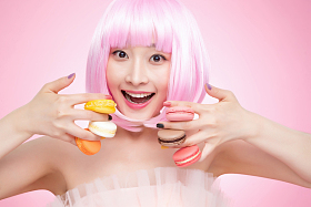 手指夹着马卡龙的年轻女孩