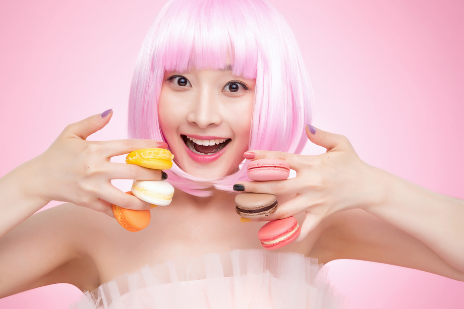 手指夹着马卡龙的年轻女孩 手指夹着马卡龙的年轻女孩