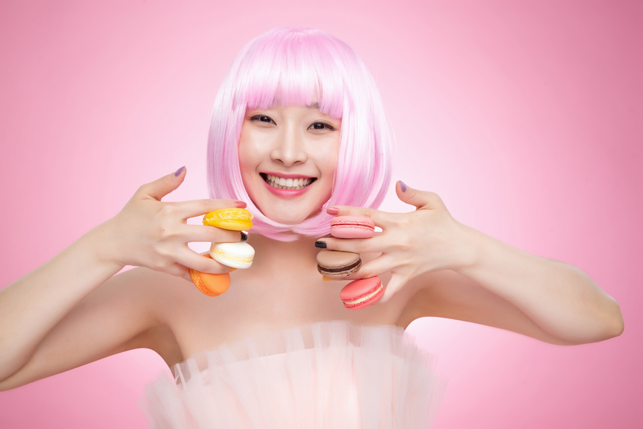 手指夹满马卡龙的年轻女孩图片