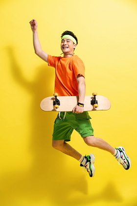 拿着滑板跳跃的青年男人图片
