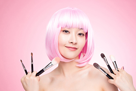 手指夹满化妆刷的年轻女孩图片