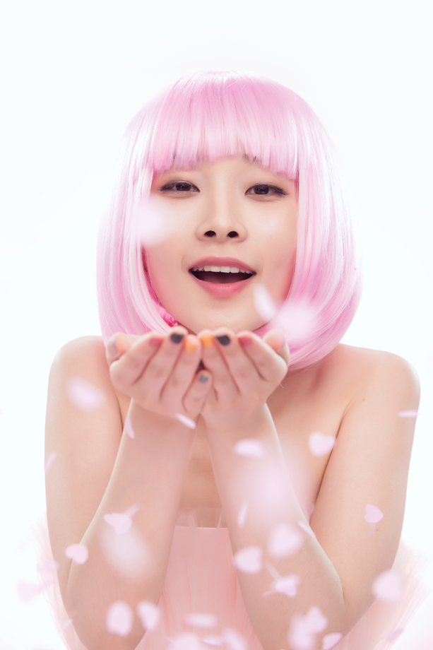 年轻女孩吹撒手中的心形纸片图片 年轻女孩吹撒手中的心形纸片图片