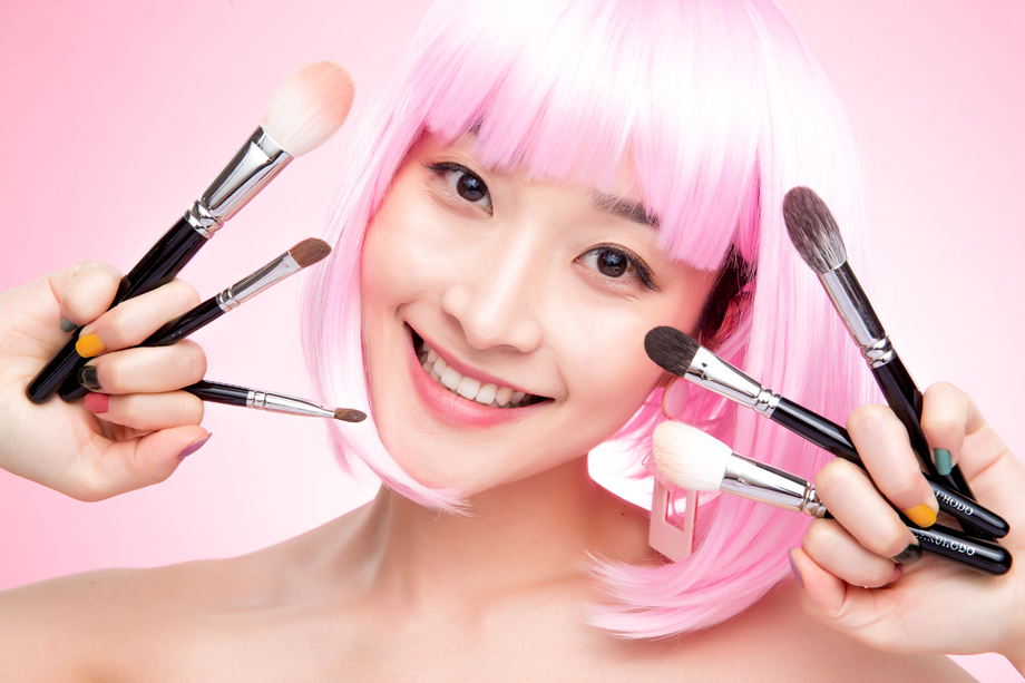 手指夹满化妆刷的年轻女孩图片