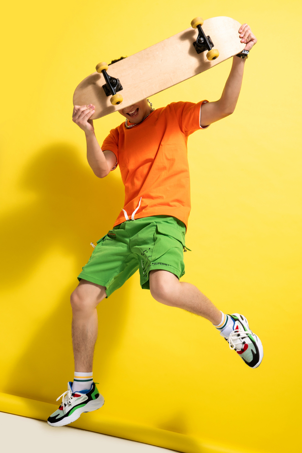 举着滑板跳跃的青年男人图片