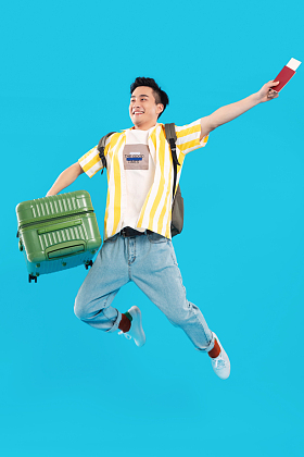 拎着行李箱跳跃的年轻男人图片