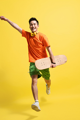 拿着滑板跳跃的快乐青年男人图片