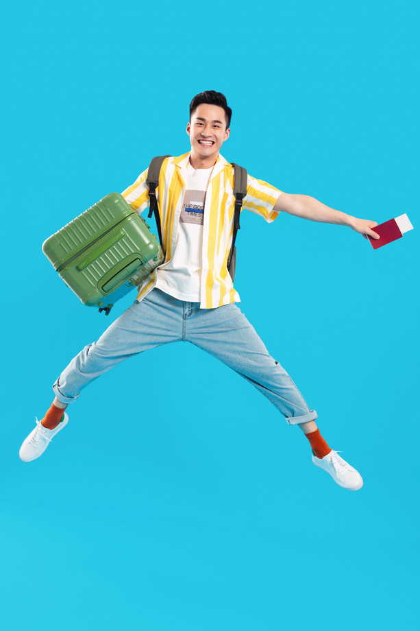 抱着行李箱跳跃的年轻男人图片
