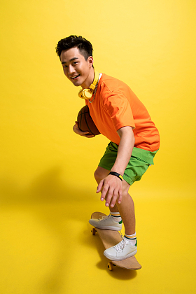 抱着篮球滑着滑板的青年男人图片