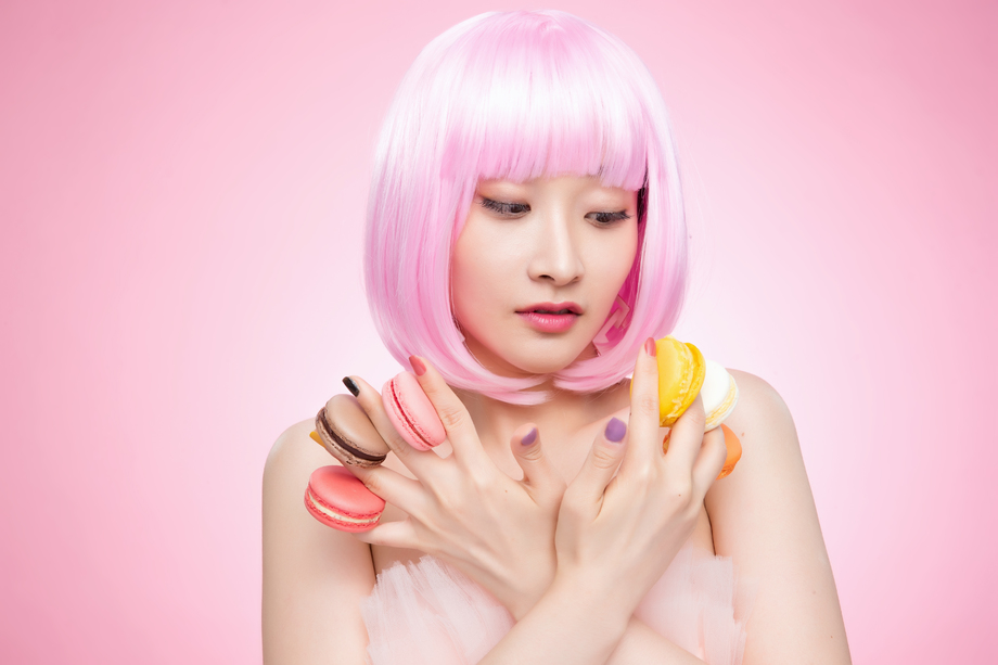 看着手指夹满马卡龙的年轻女孩 看着手指夹满马卡龙的年轻女孩