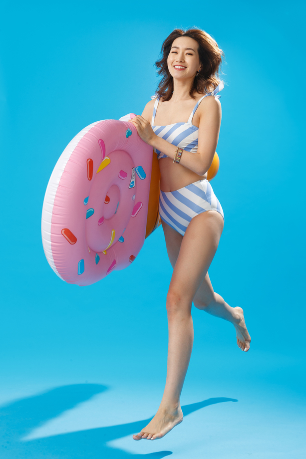 抱着冰淇淋形状的浮排跳跃的泳装美女