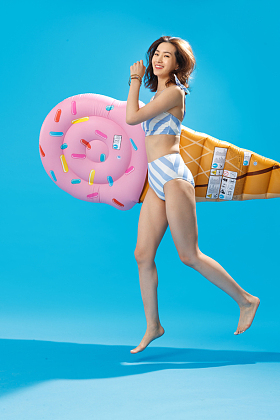 抱着冰淇淋形状的浮排跳跃的比基尼美女