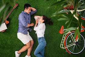 幸福的青年伴侣面对面躺在草地上