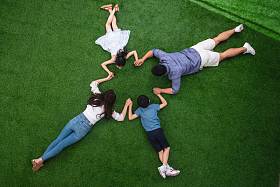 幸福的一家四口手牵着手趴在草地上