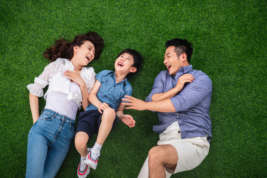 快乐的一家三口躺在草地上嬉戏 快乐的一家三口躺在草地上嬉戏