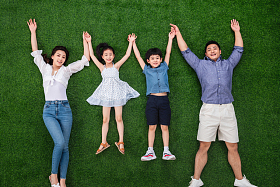 幸福的一家四口手牵手躺在草地上