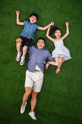 在草地上父亲驮着儿子和女儿