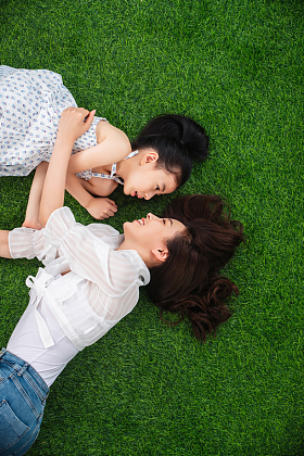 幸福的母女躺在草地上玩耍