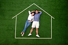 青年伴侣躺在草地上的房子轮廓