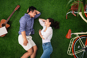 幸福的青年伴侣躺在草地上享受甜蜜时光