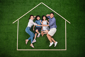 快乐的一家四口躺在草地上的房子轮廓