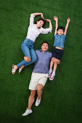 在草地上青年男人驮着妻子和儿子