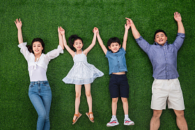 幸福的一家四口手牵手躺在草地上