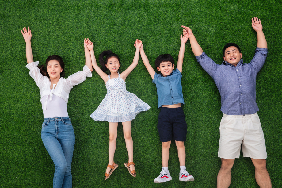 幸福的一家四口手牵手躺在草地上