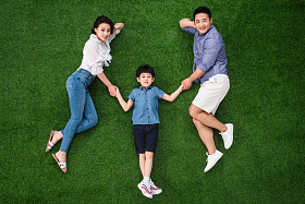 幸福的一家三口手牵手躺在草地上