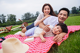 幸福的一家三口侧卧在野餐垫上