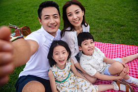 幸福的一家四口坐在野餐垫上自拍