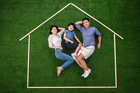 快乐的一家三口躺在草地上的房子轮廓