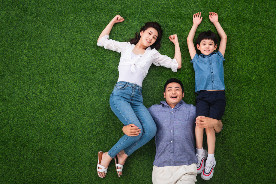 在草地上青年男人驮着妻子和儿子 在草地上青年男人驮着妻子和儿子