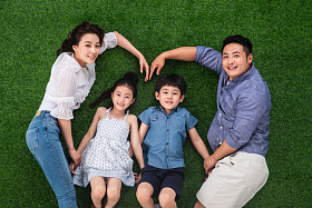 幸福的一家四口躺在草地上组成心形