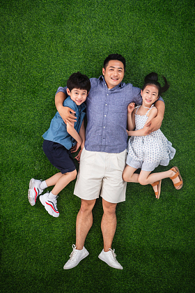 父亲搂着儿子和女儿躺在草地上