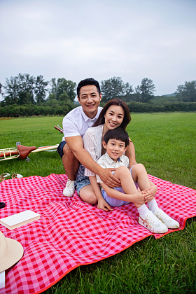 幸福的一家三口坐在野餐垫上图片