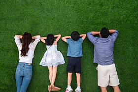 幸福的一家四口趴在草地上照片