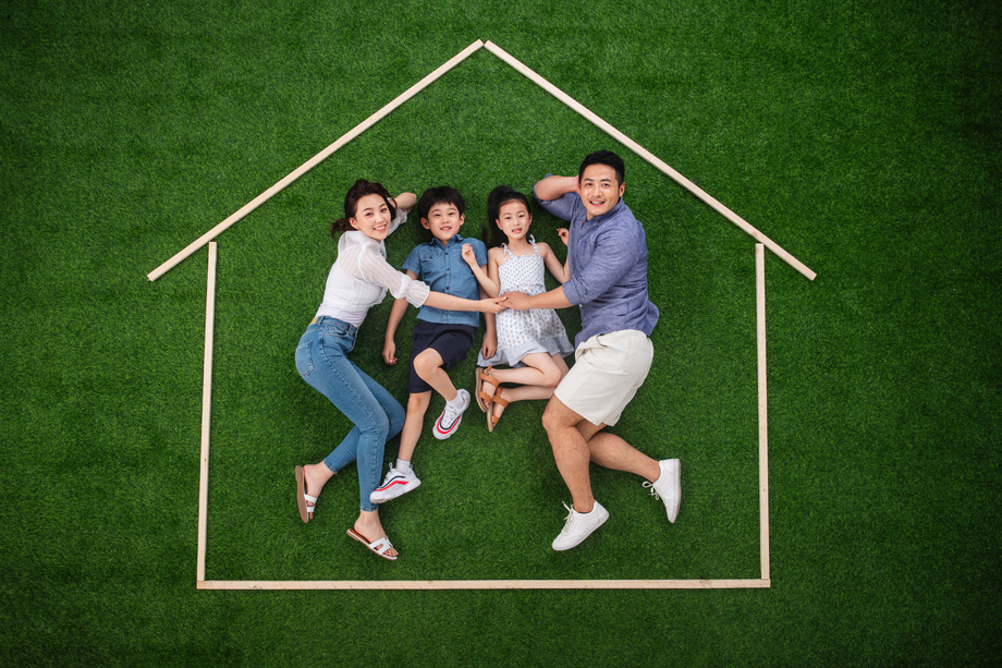 快乐的一家四口躺在草地上的房子轮廓