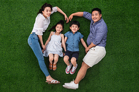 幸福的一家四口躺在草地上组成心形