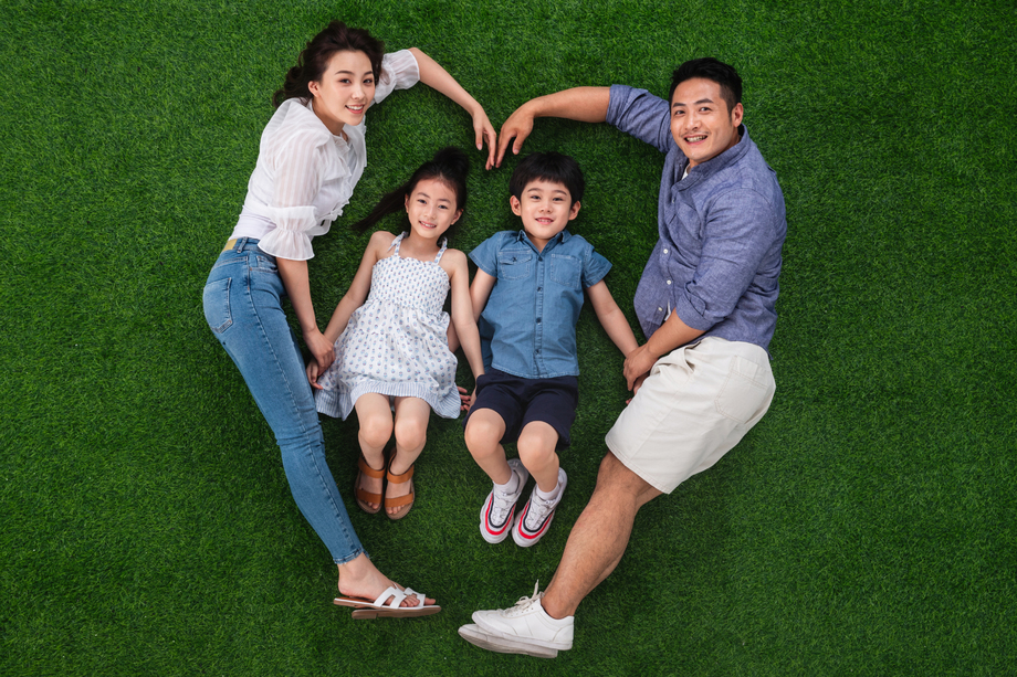 幸福的一家四口躺在草地上组成心形