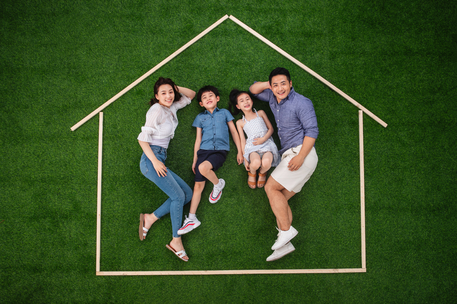 快乐的一家四口躺在草地上的房子轮廓