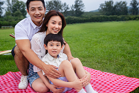 幸福的一家三口坐在野餐垫上照片
