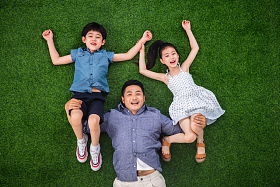 在草地上父亲驮着儿子和女儿