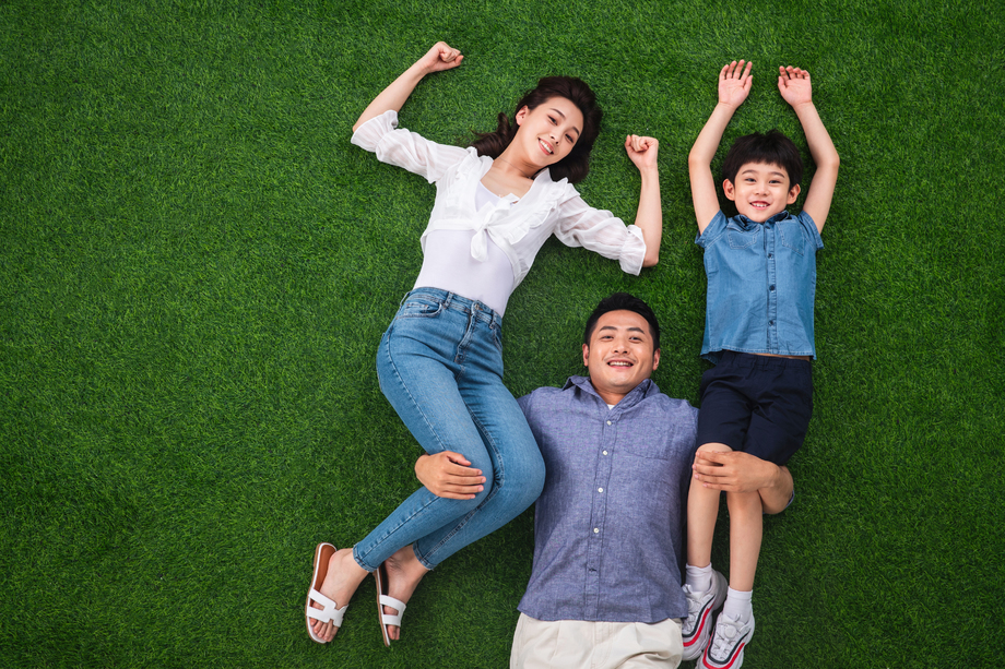 在草地上青年男人驮着妻子和儿子