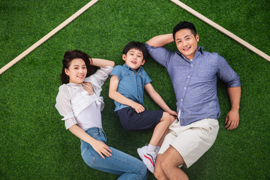 快乐的一家三口躺在草地上的房子轮廓