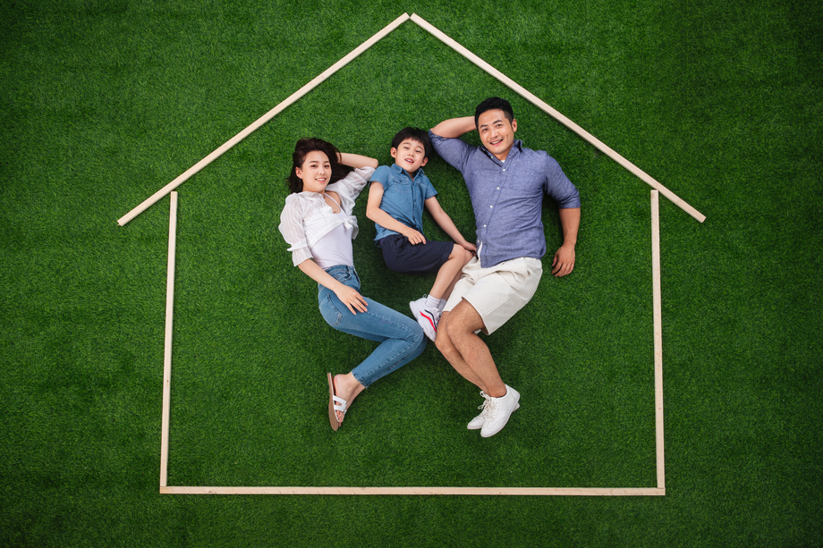 快乐的一家三口躺在草地上的房子轮廓