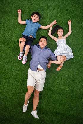 在草地上父亲托举儿子和女儿图片