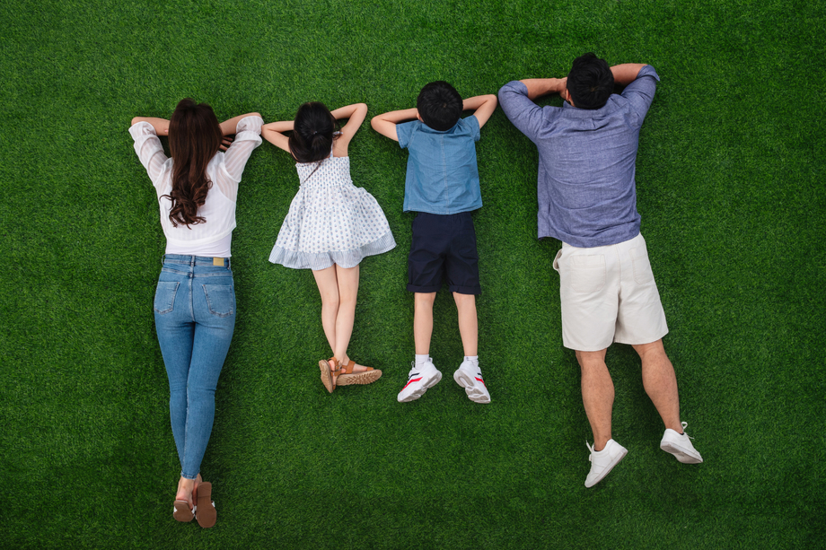 幸福的一家四口趴在草地上照片